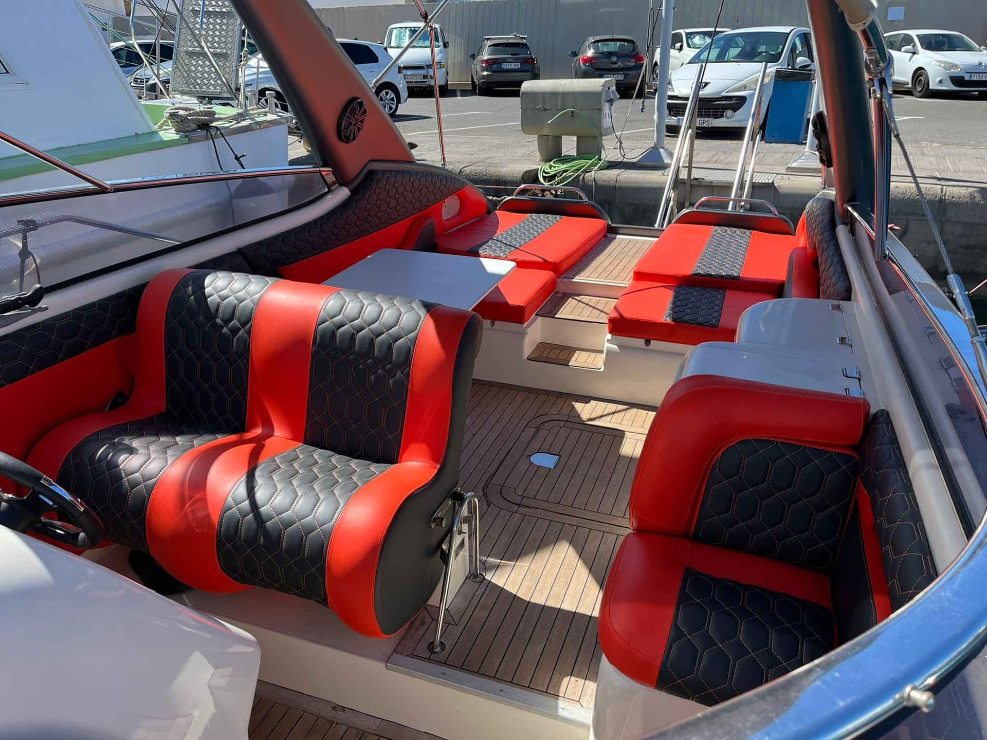 Asientos tapizados en rojo y negro dentro de una lancha motora atracada en un puerto.
