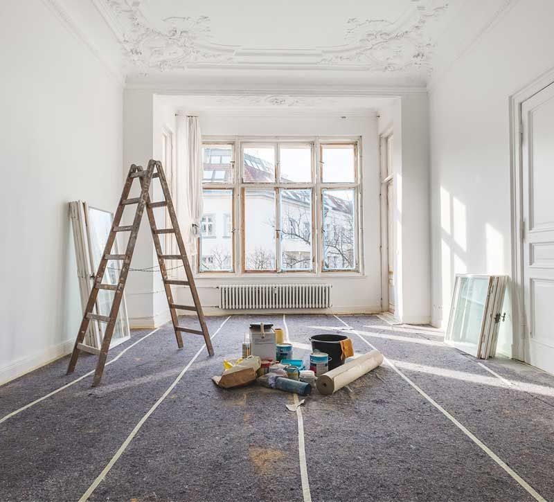 Reforma de habitación con escalera, herramientas, materiales y gran ventanal.