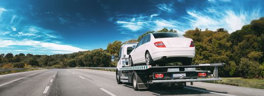 Berline blanche chargée sur un véhicule de transport roulant sur l'autoroute
