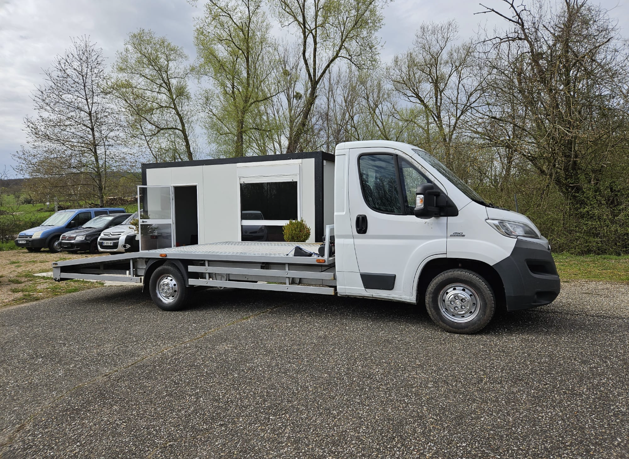 Camion-plateau blanc stationné sur du gravier à côté d'arbres