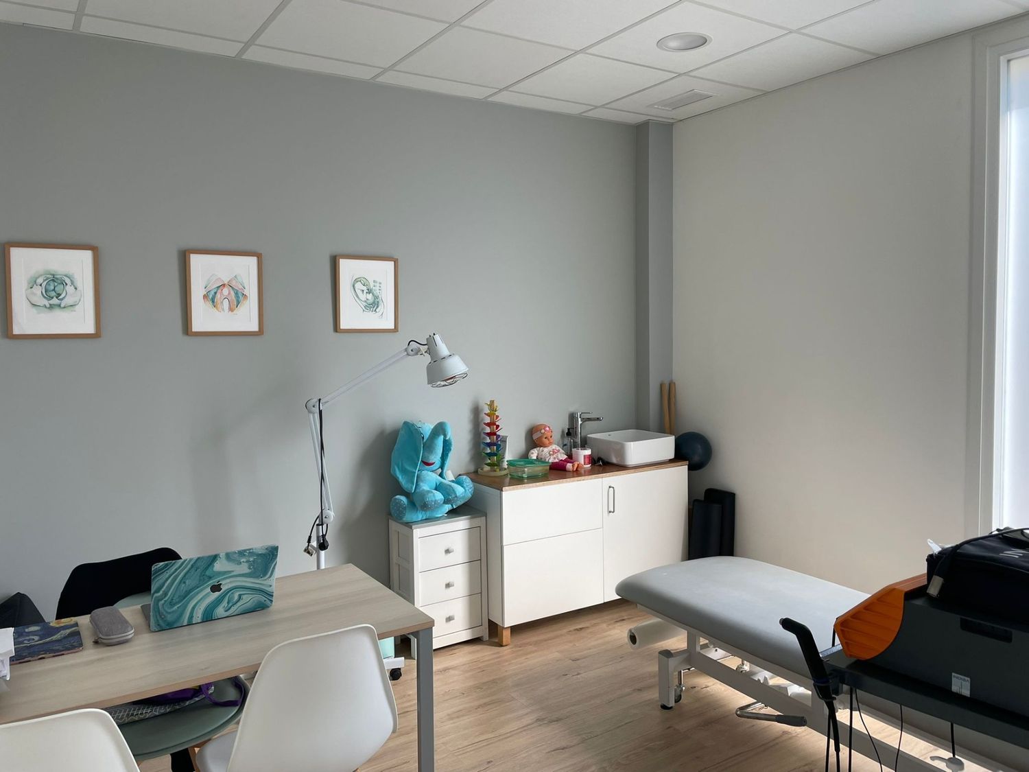 Un consultorio médico con una mesa y sillas y una mesa de masaje.