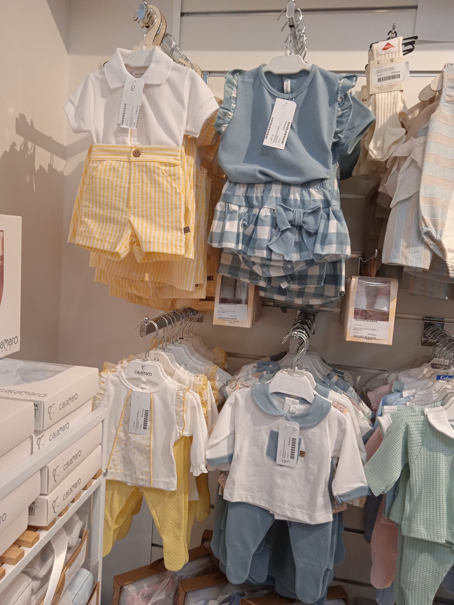 Una tienda llena de ropa de bebé colgada en percheros.