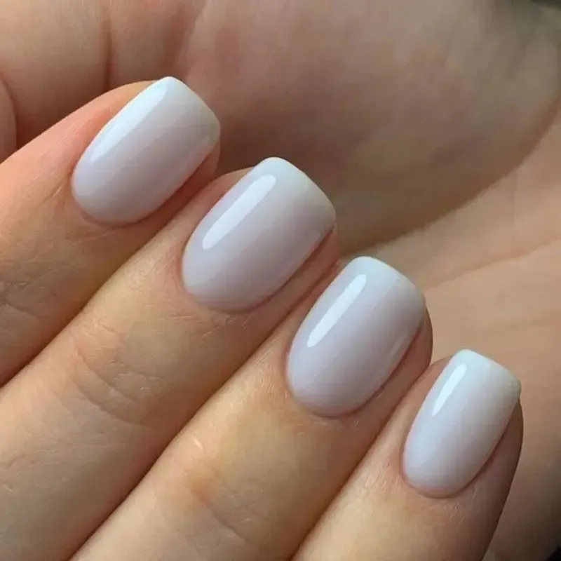 Primer plano de una mano con uñas pintadas de color rosa pálido brillante.