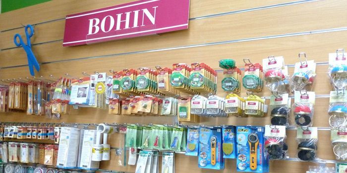 Présentoir de la marque BOHIN en magasin, mettant en vedette divers outils et accessoires de couture.