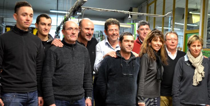 Groupe de personnes posant ensemble à l'intérieur, certaines les bras sur les épaules les unes des autres ; expressions neutres.