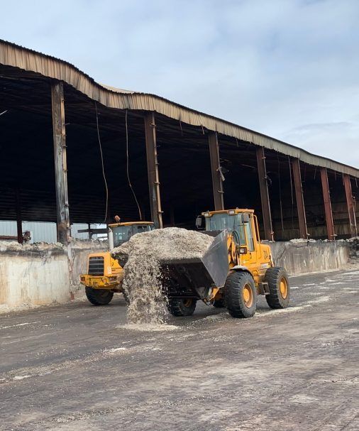 Una excavadora amarilla está cargando arena en un almacén.