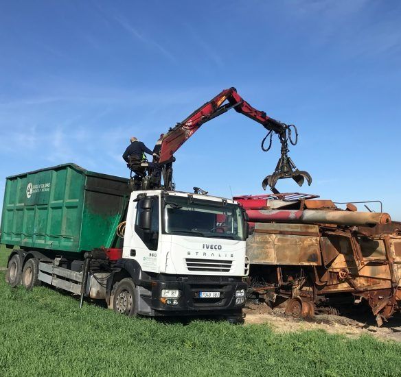 Un camión Iveco se está cargando con un contenedor verde.
