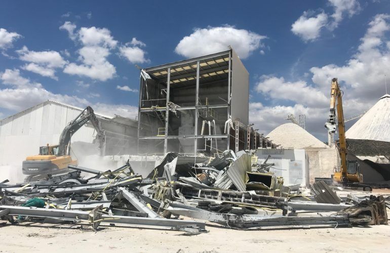 Un gran edificio está siendo demolido por una excavadora.