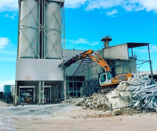 Una excavadora amarilla está trabajando frente a un edificio.
