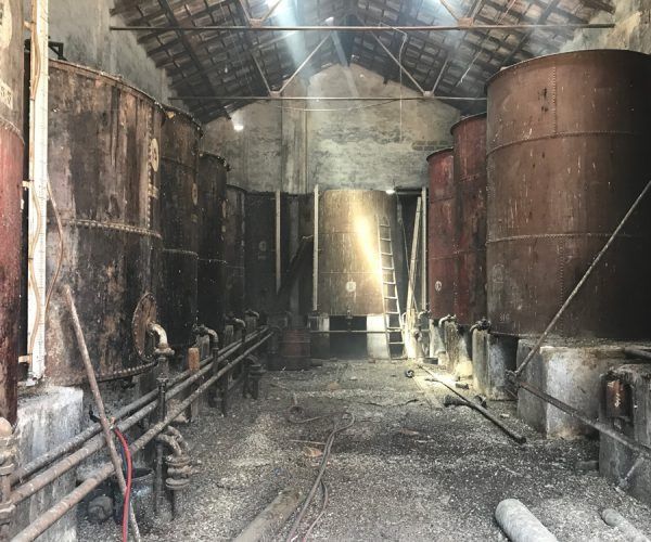 Un almacén lleno de tanques y tuberías oxidadas.