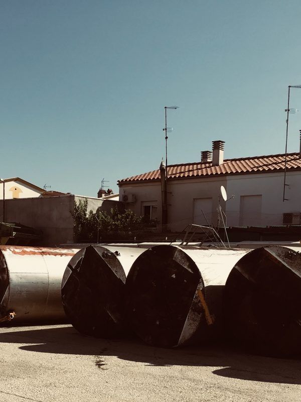 Una fila de grandes cilindros de metal están estacionados frente a una casa