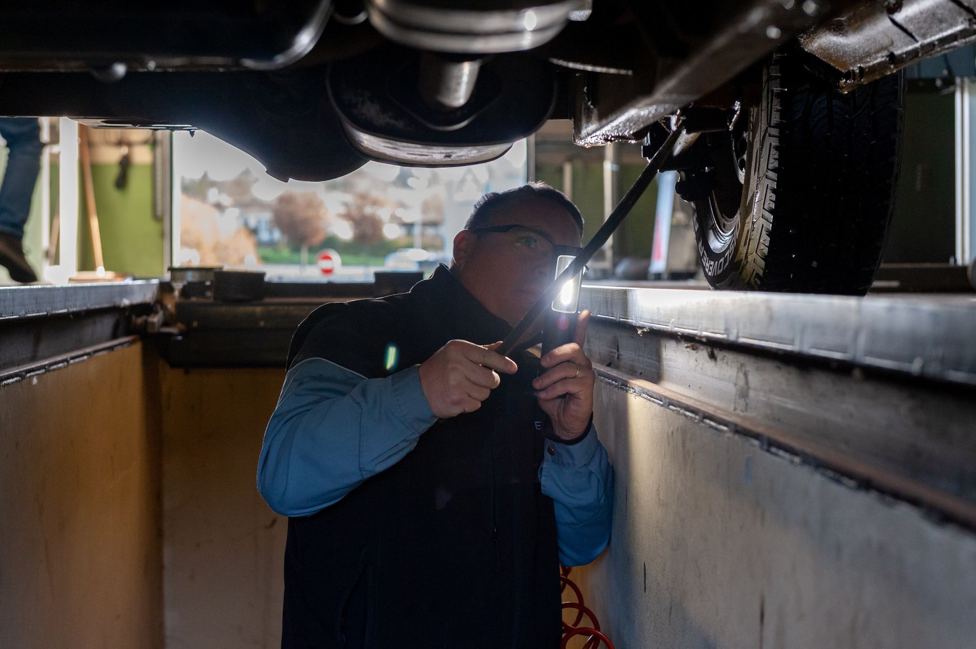 Un mécanicien inspecte le dessous de la voiture.