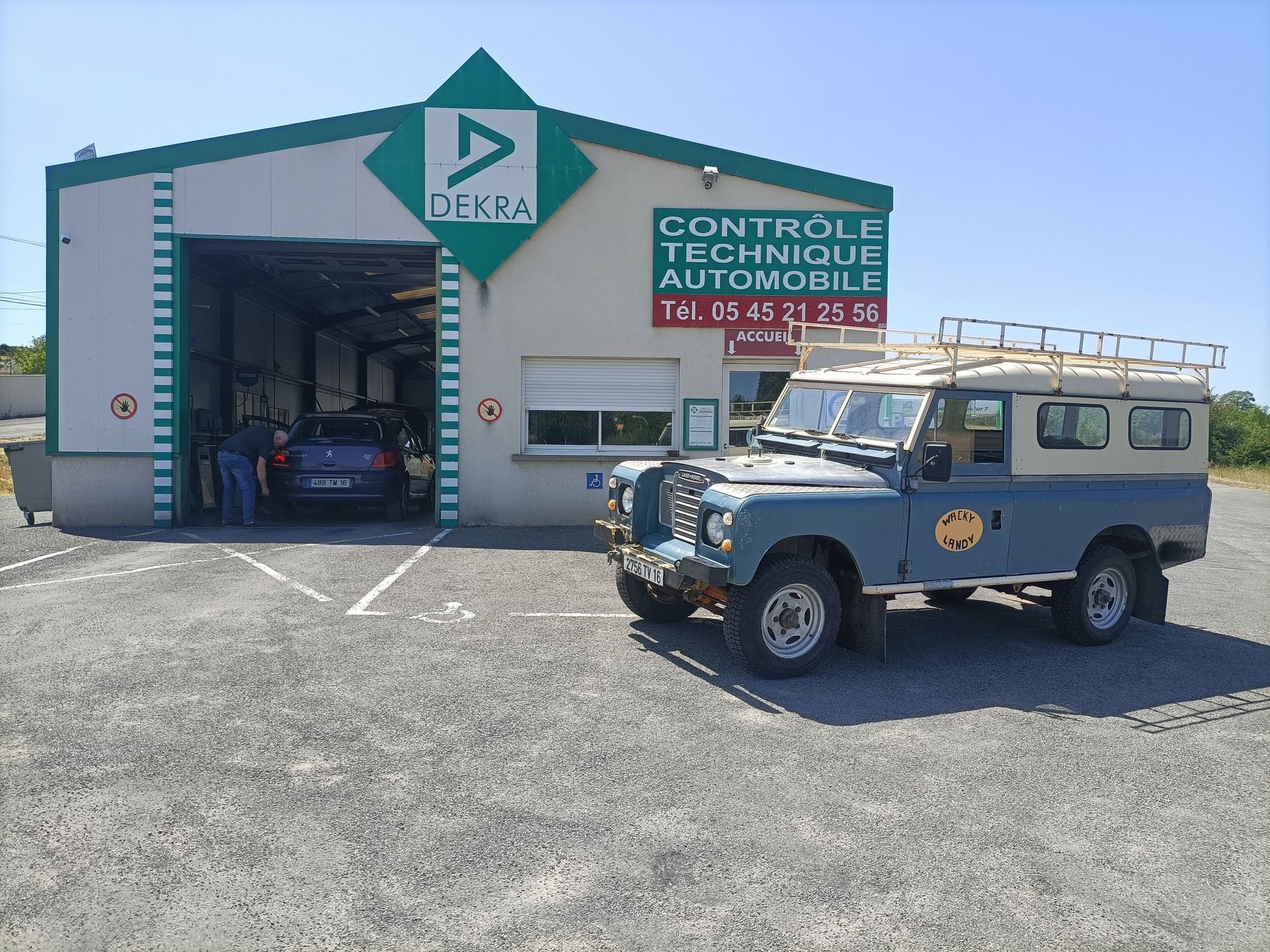 Un Land Rover bleu est garé devant un centre de contrôle technique DEKRA.
