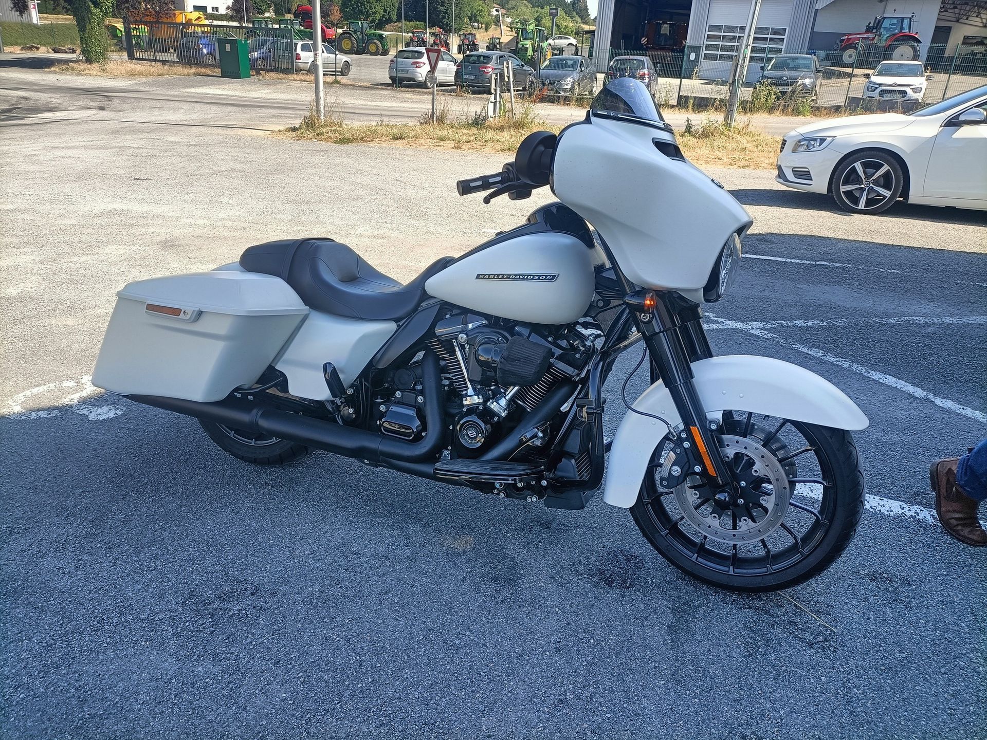 Moto Harley-Davidson Street Glide blanche garée devant le centre.