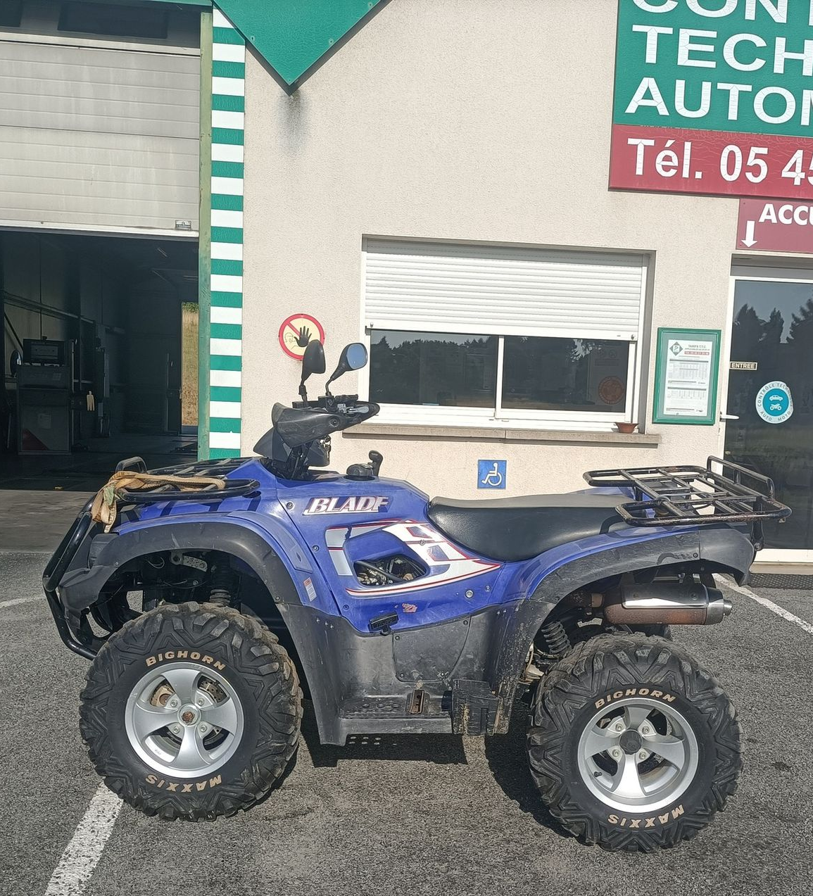 Un quad bleu est stationné devant le centre de contrôle.