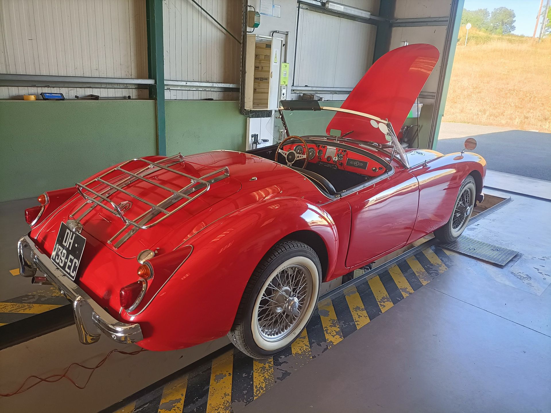 Décapotable classique rouge, capote ouverte et porte-bagages.