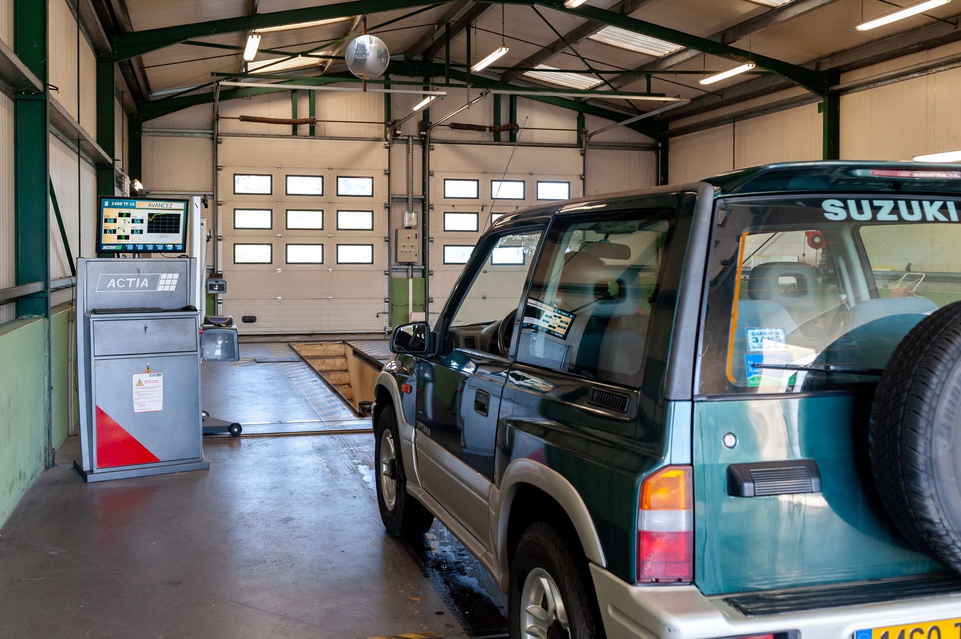 Un SUV Suzuki vert à l'intérieur d'un centre de contrôle technique.
