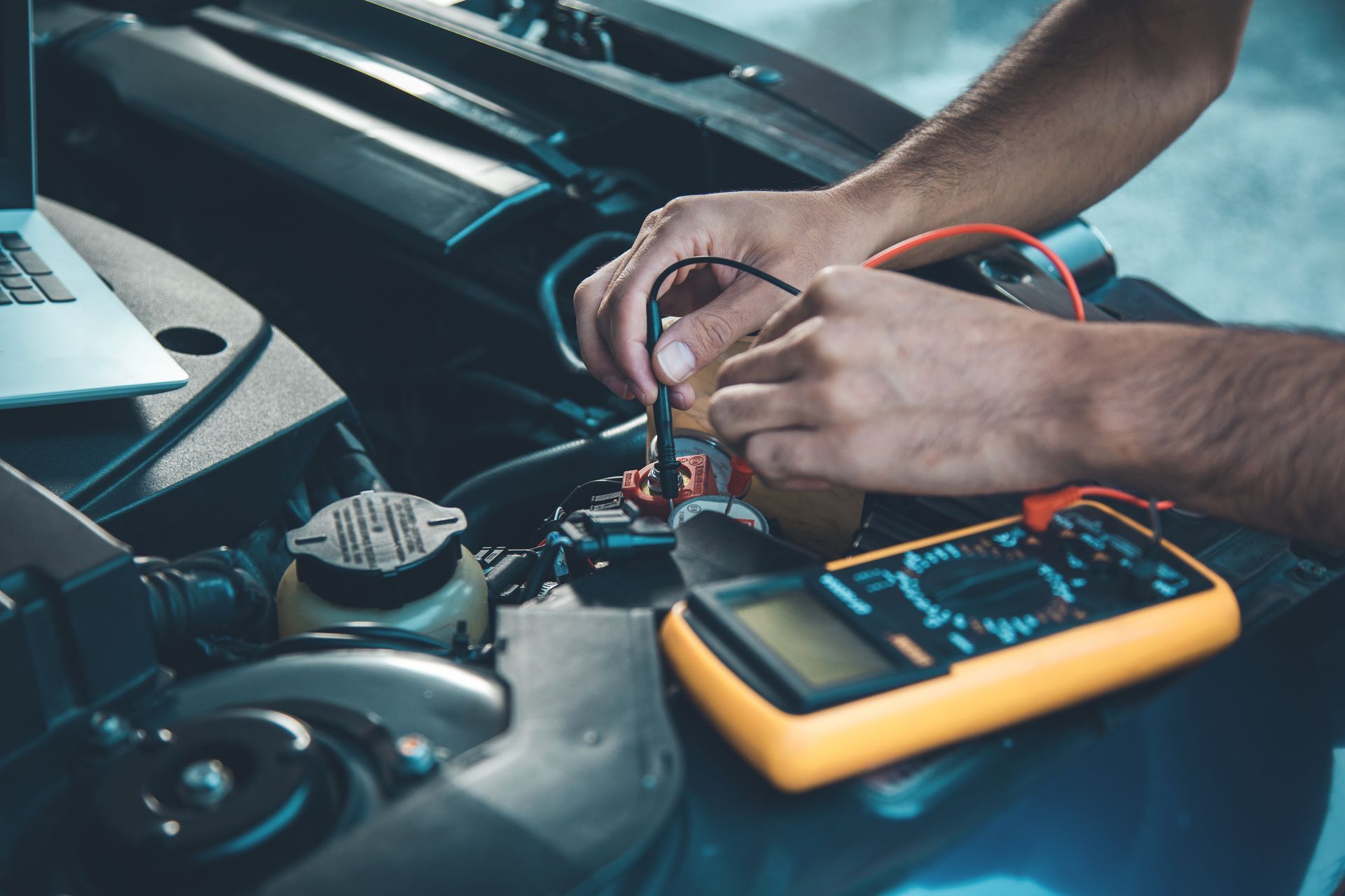 Des mains utilisent un multimètre pour tester un composant du moteur d'une voiture.