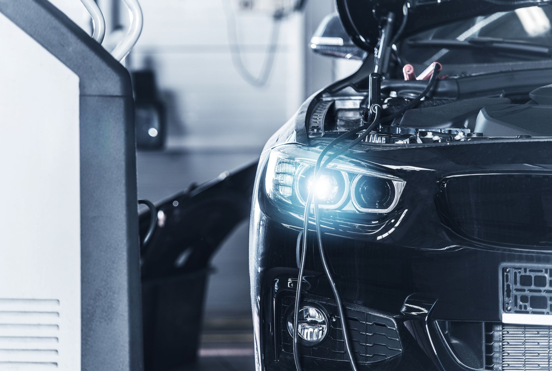 Voiture noire, capot ouvert, phare allumé, en cours de contrôle.