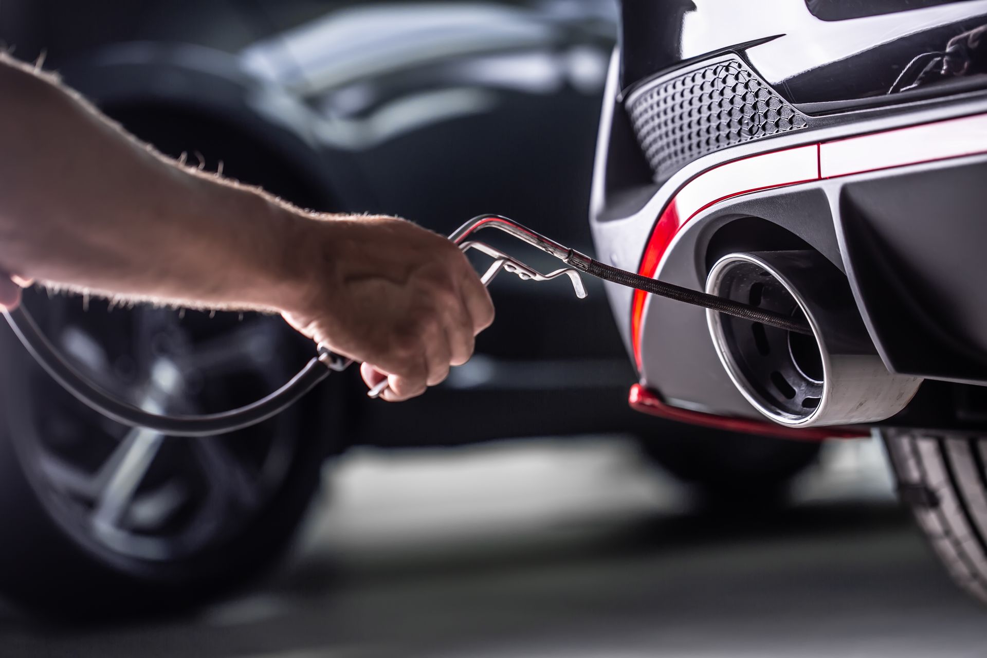 Main tenant le tuyau dans le pot d'échappement d'une voiture pour un test d'émissions.