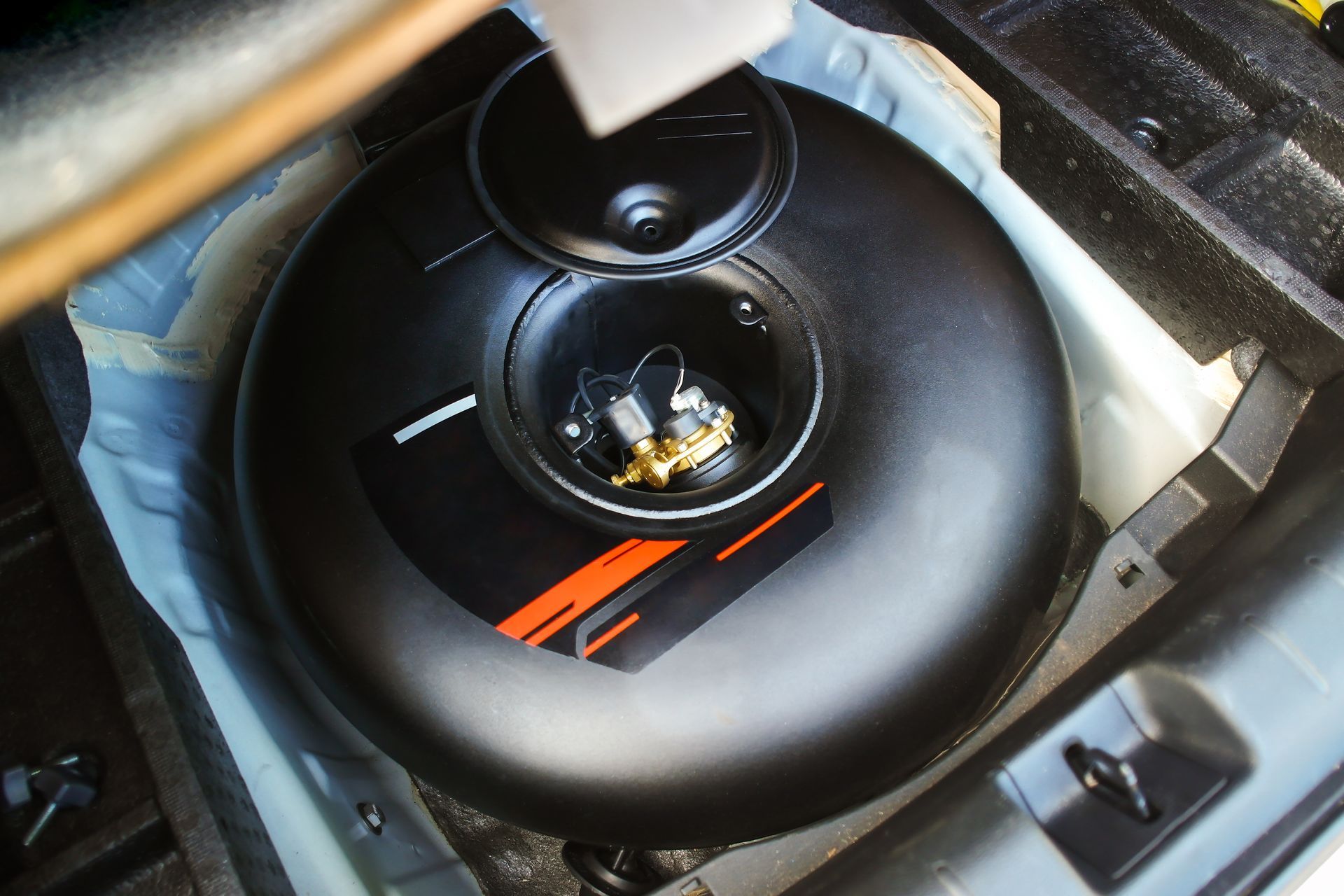 Réservoir de gaz naturel noir et circulaire installé dans le coffre d'une voiture.