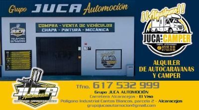 Local comercial de «Grupo Juca Automoción» y «Juca Camper», con carteles azules y texto de contacto en amarillo.