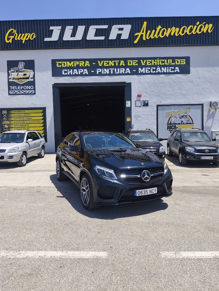Coche negro aparcado frente al concesionario de Grupo JICA Automoción, con otros coches delante de la sala de exposición