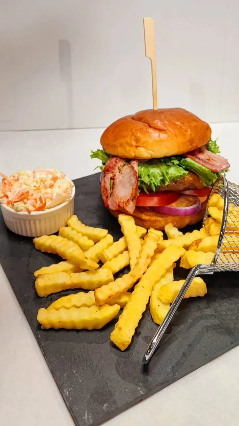 Sándwich de salchicha en un plato blanco con texto, en un entorno de cafetería.