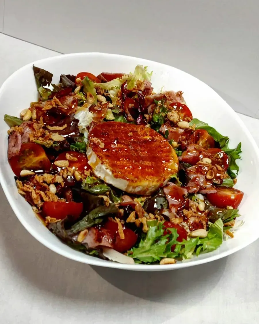 Sándwich de salchicha en un plato blanco con texto, en un entorno de cafetería.