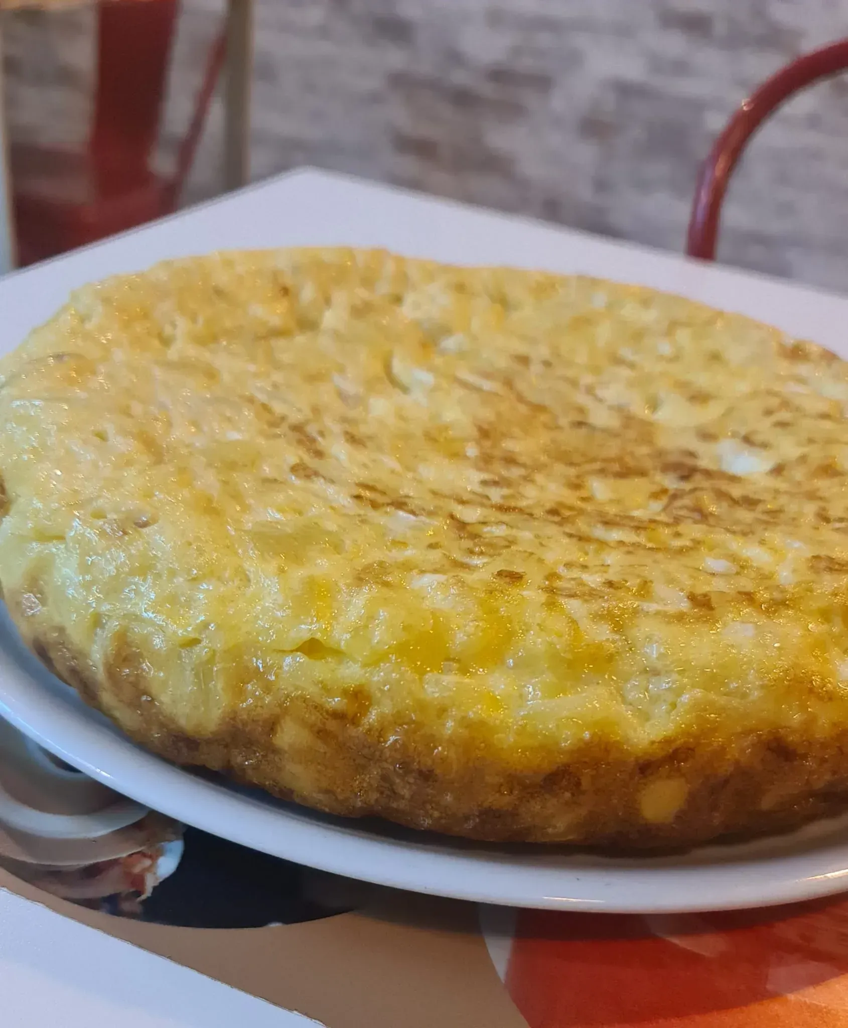 Una tortilla española de patatas dorada servida en un plato blanco.