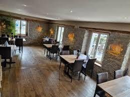 Ein Speisesaal mit rustikalen Steinwänden, Holzböden und mehreren Tischen mit Stühlen, die zum Servieren bereitstehen.