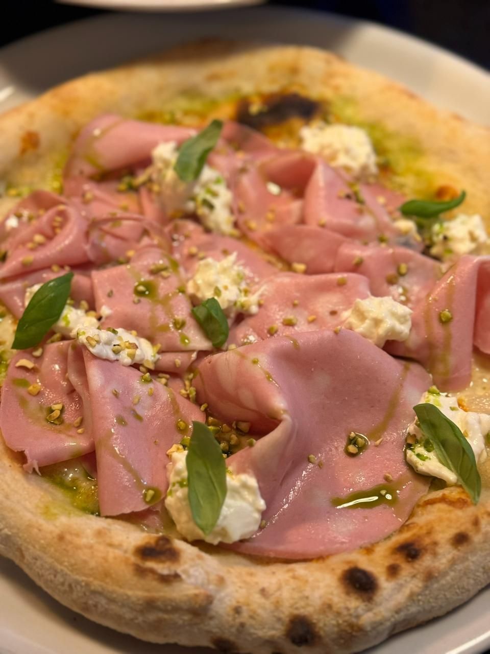 Pizza mit Mortadella, Ricotta, Pistazien und Basilikum.