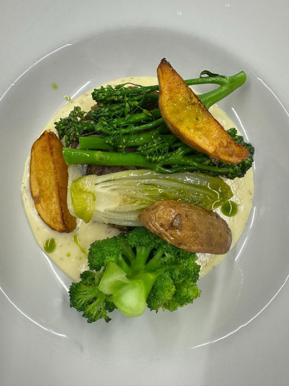 Speiseteller: Gebratenes Gemüse, darunter Brokkoli, Broccolini, Kartoffeln und Salat, in cremiger Sosse.