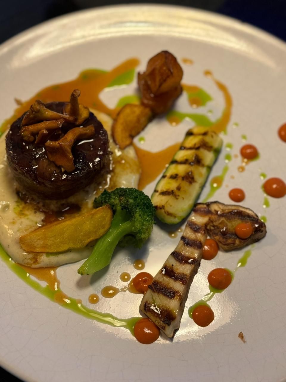 Teller mit Gourmetgerichten: angebratenes Fleisch, gegrilltes Gemüse und kunstvoll angerichtete Saucen.