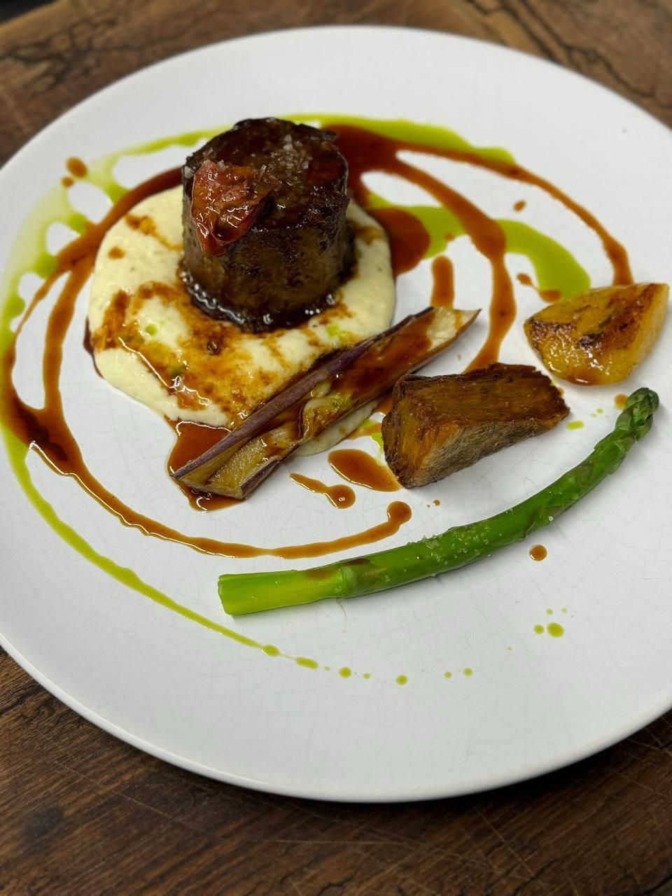 Gourmetteller: Gebratenes Fleischmedaillon auf Kartoffelpüree, dazu geröstetes Gemüse, Spargel und dekorative Saucen.