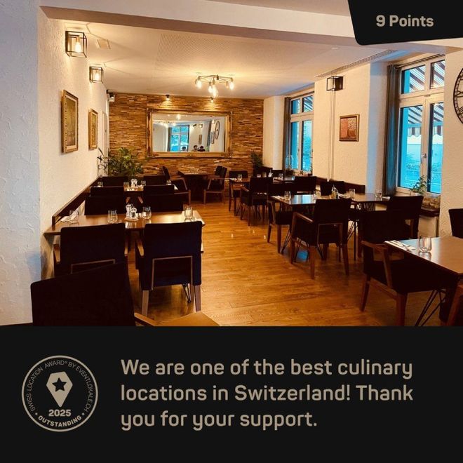 Innenansicht eines Restaurants mit Tischen, Stühlen und einem dekorativen Spiegel. Text: Beste kulinarische Lage in der Schweiz.