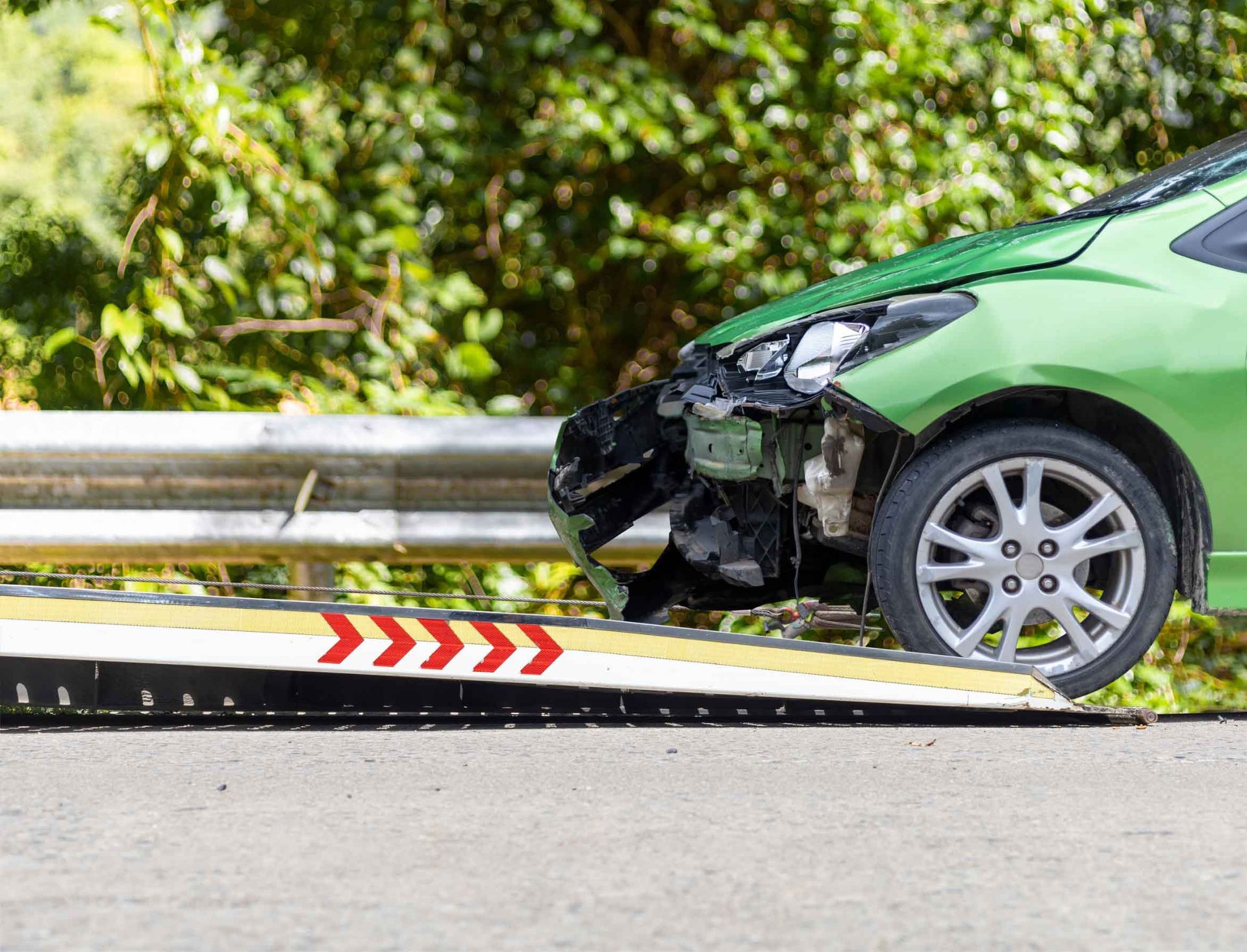 Un coche verde está siendo remolcado por una grúa.