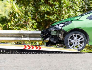 Un coche verde está siendo remolcado por una grúa.