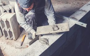 Ouvrier déposant du mortier sur un mur de parpaings en construction