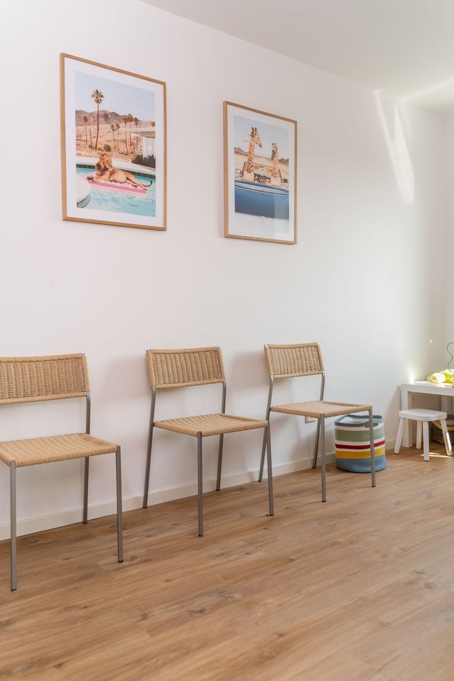 Eine Stuhlreihe in einem Wartezimmer mit Bildern an der Wand.