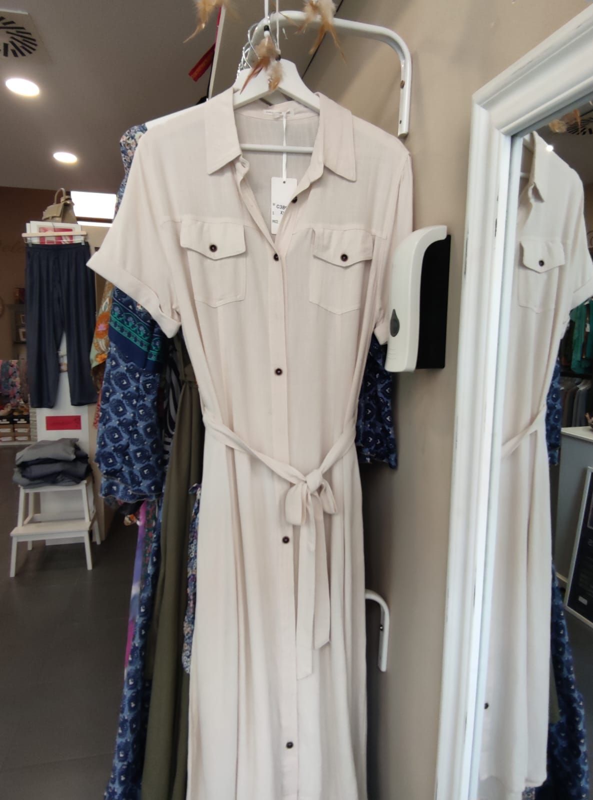 Un vestido blanco está colgado delante de un espejo.