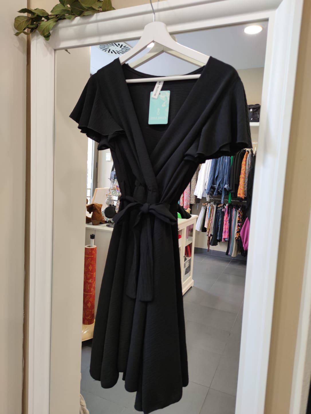 Un vestido negro está colgado frente a un espejo.