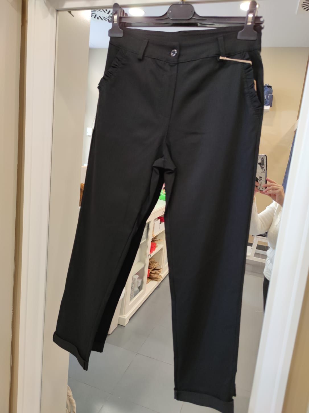 Un par de pantalones negros colgados en una percha frente a un espejo.