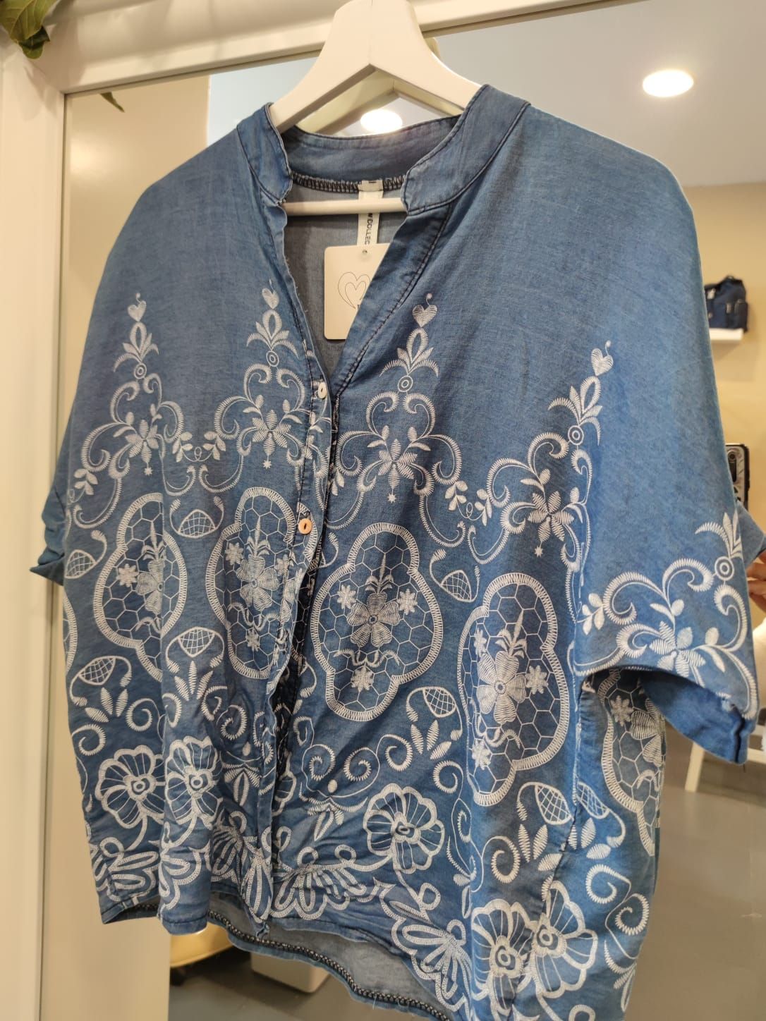 Una camisa azul con flores blancas está colgada en una percha.