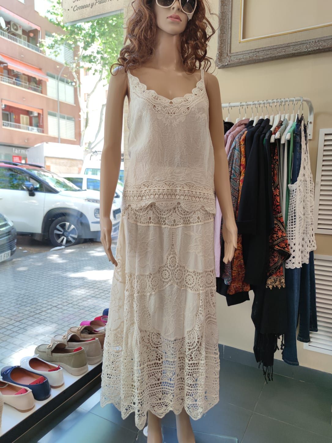 Un maniquí lleva un vestido de encaje blanco y gafas de sol.