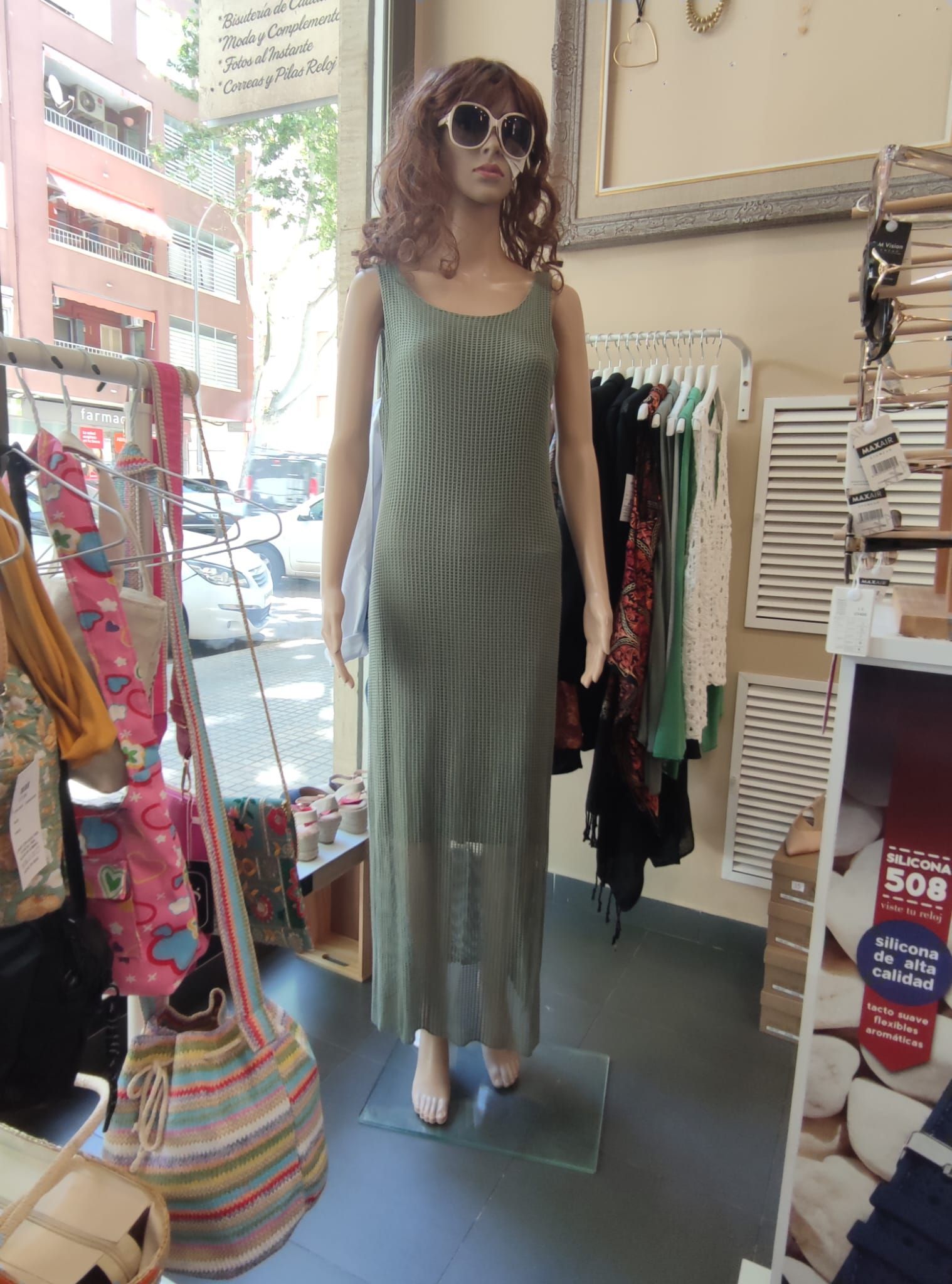 Un maniquí lleva un vestido verde y gafas de sol en una tienda.