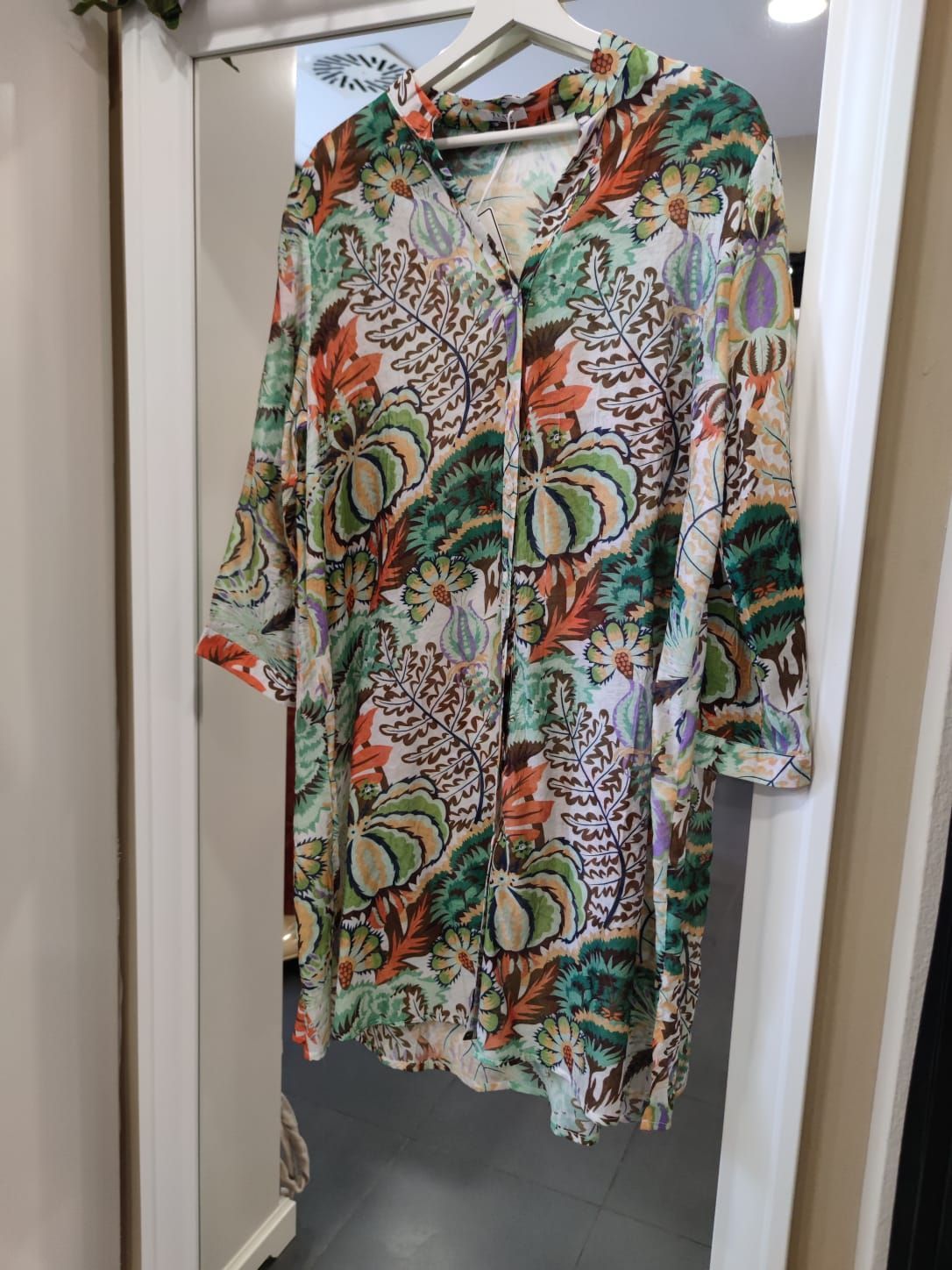 Una camisa colorida está colgada en una percha frente a un espejo.