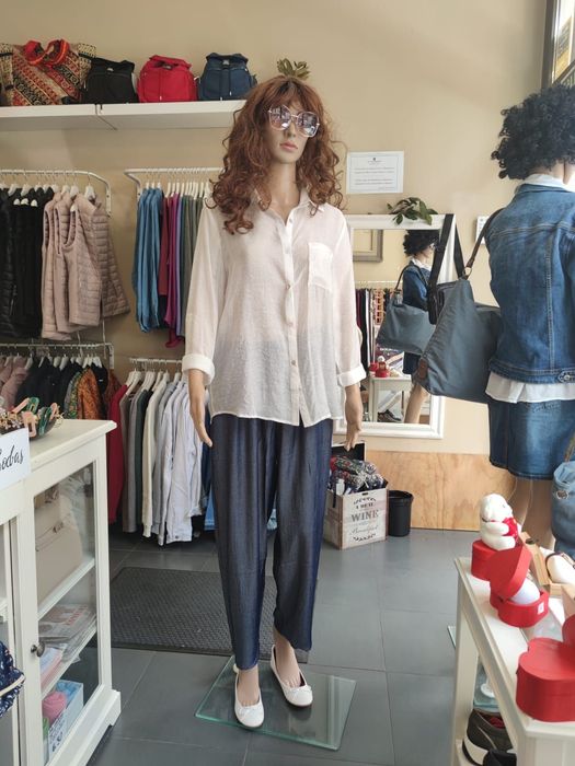 Un maniquí lleva una camisa blanca y pantalones azules.