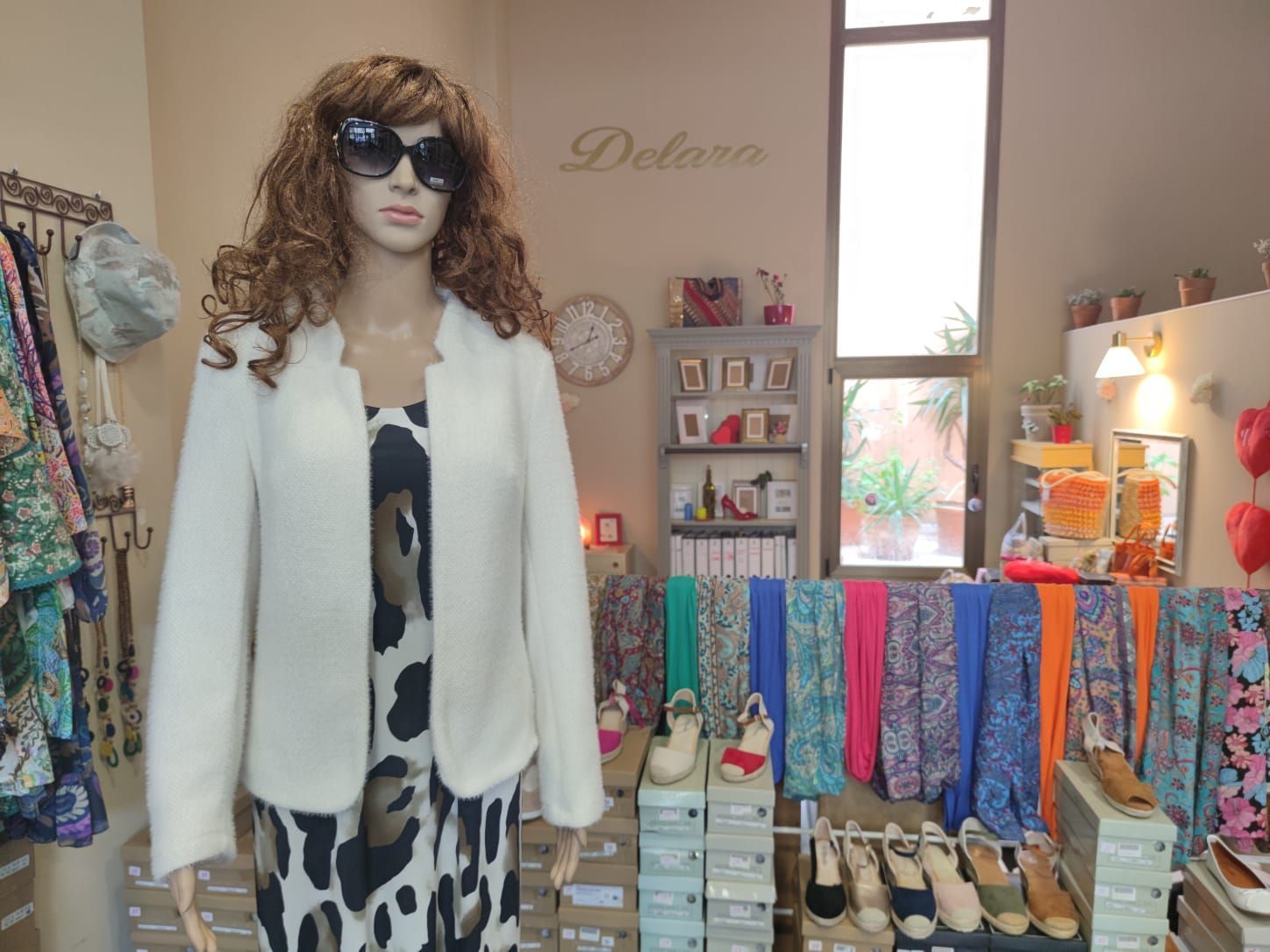 Un maniquí con gafas de sol y una chaqueta blanca en una tienda.
