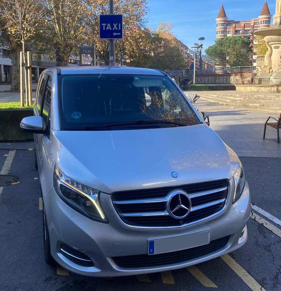 Un taxi plateado está estacionado en un estacionamiento.